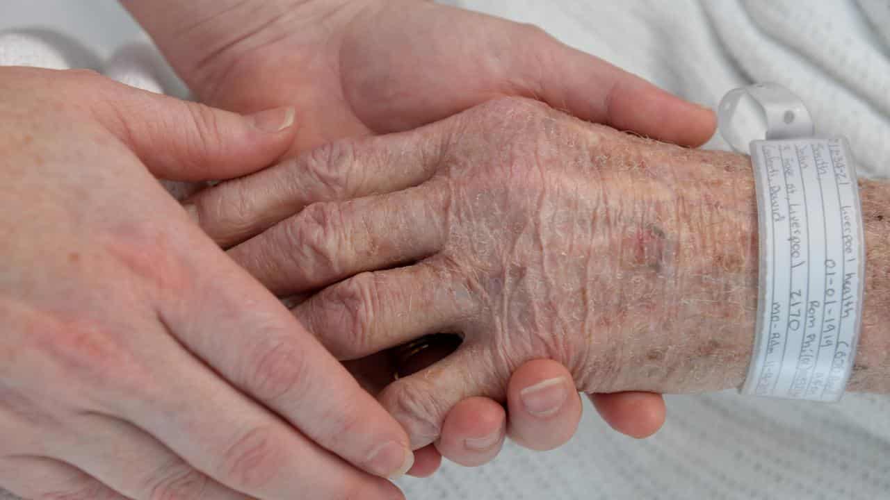 A nurse holds the hand of an elderly patient (file image)