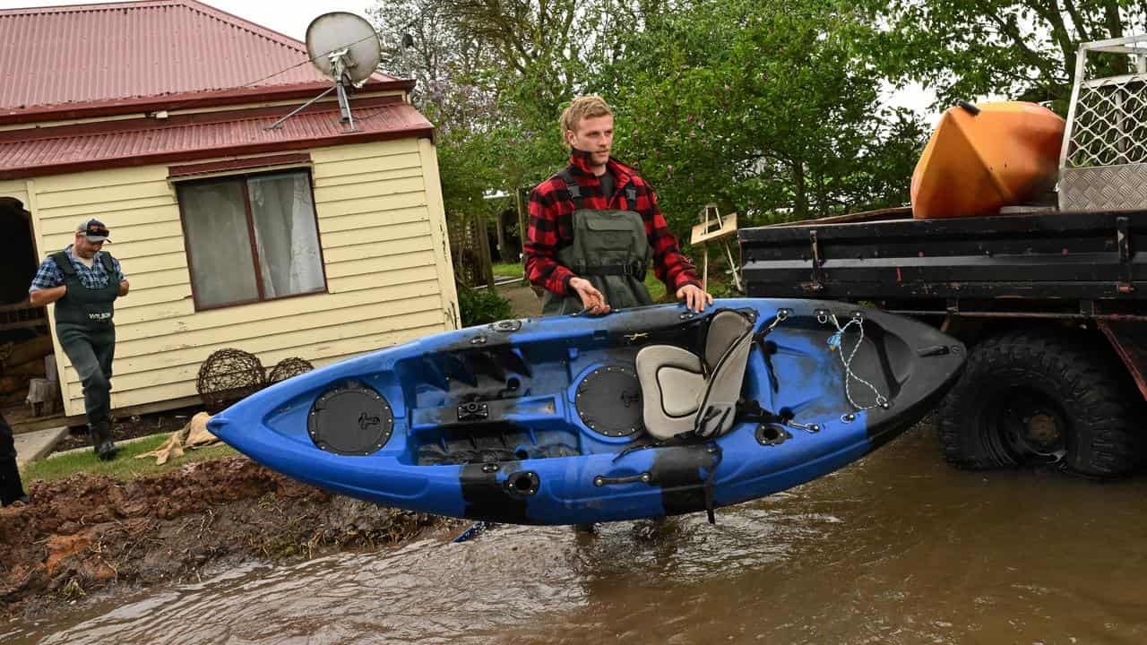 Riley Davis with a kayak in flood water in Tinamba