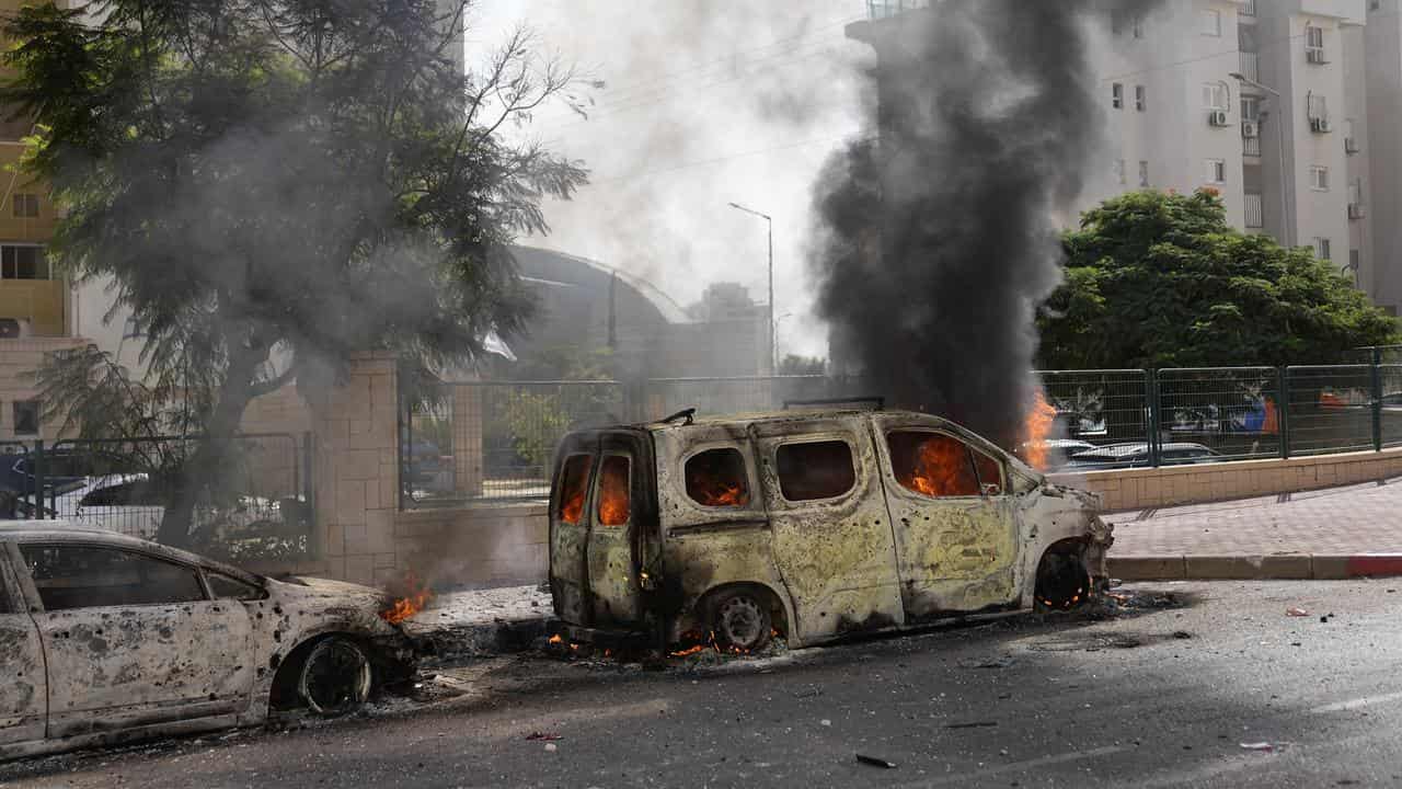 Cars are on fire after they were hit by rockets