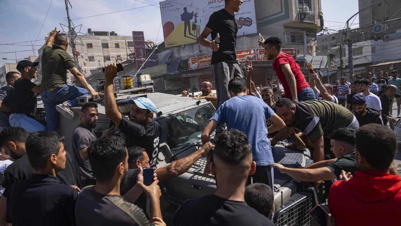 Palestinians gather around an Israeli army vehicle