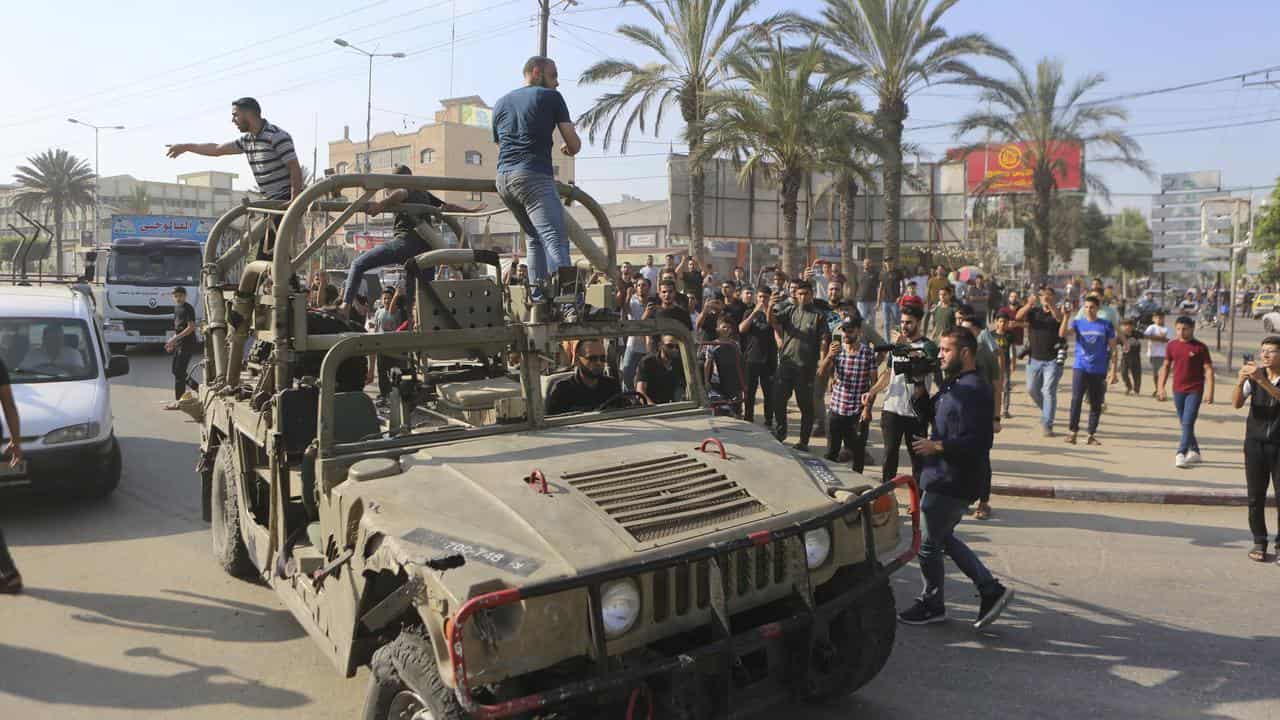 Palestinians ride on an Israeli military vehicle