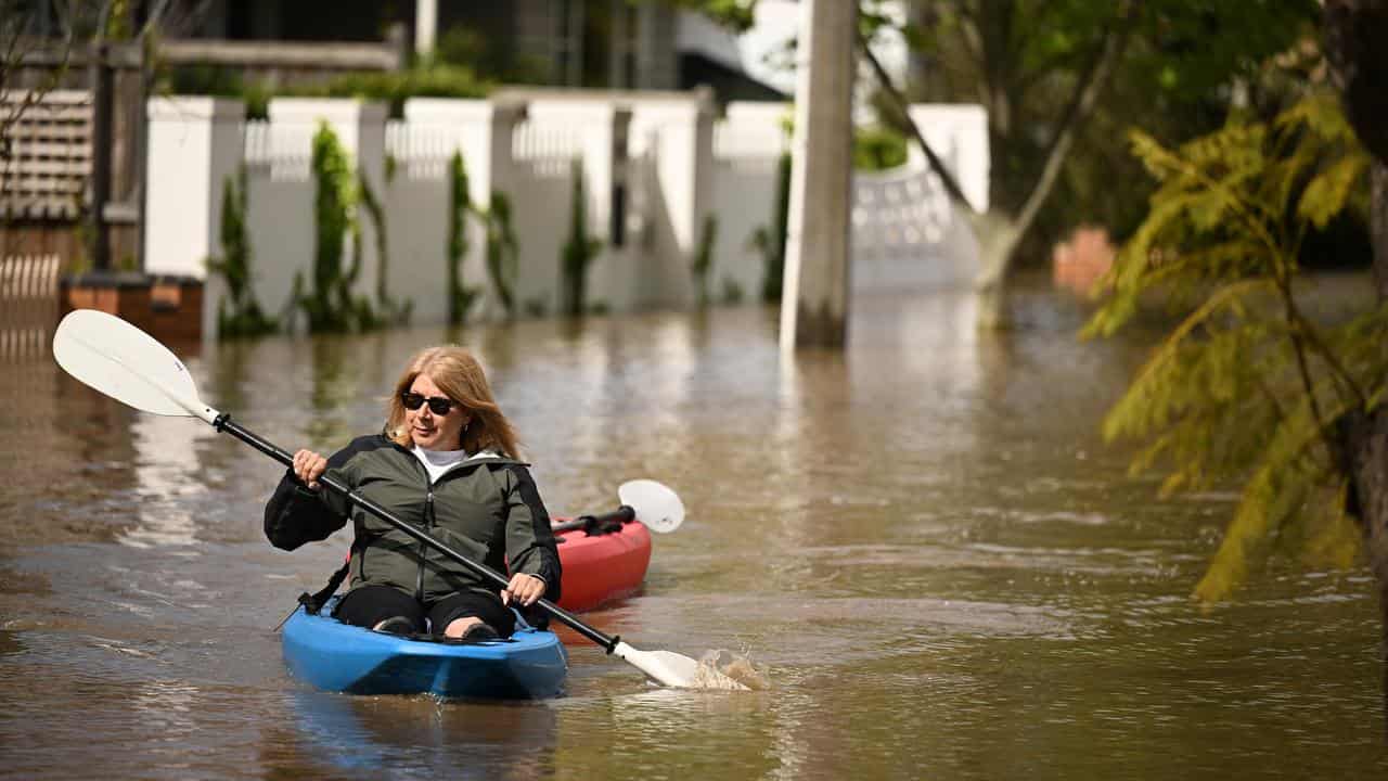 A lady canoeing along flood waters in Maribyrnong