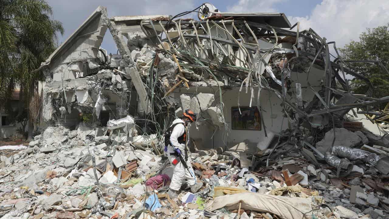 An Israeli soldier walks past a house destroyed by Hamas militants