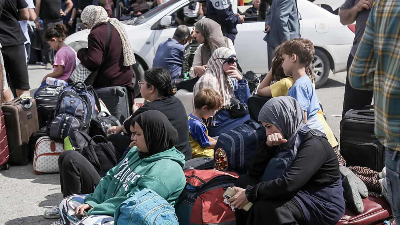 Palestinians with dual nationalities wait to cross the Rafah border