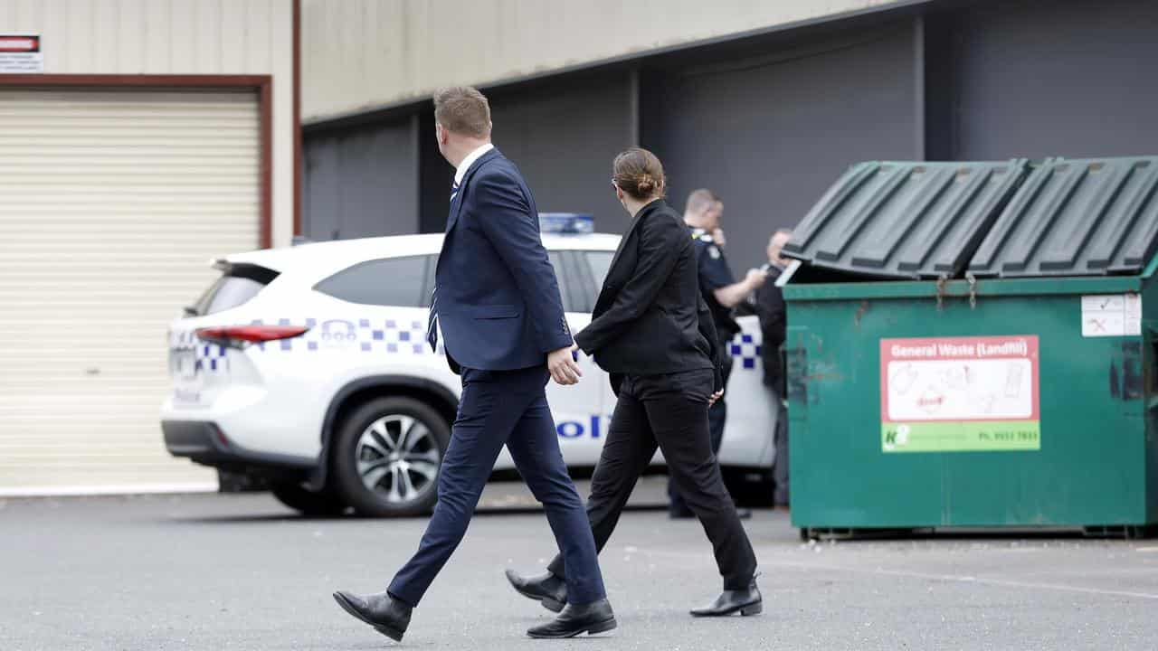 Detectives walk past police searching bin