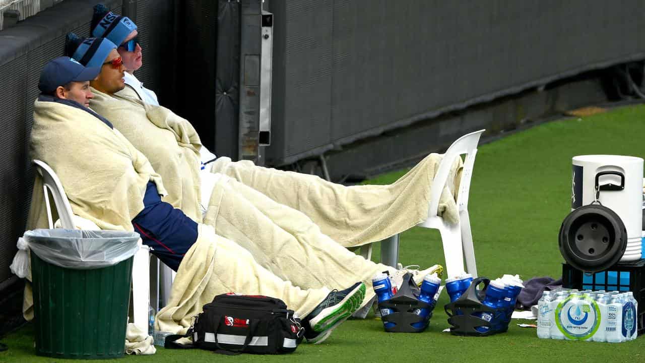 New South Wales players try to keep warm at the MCG.