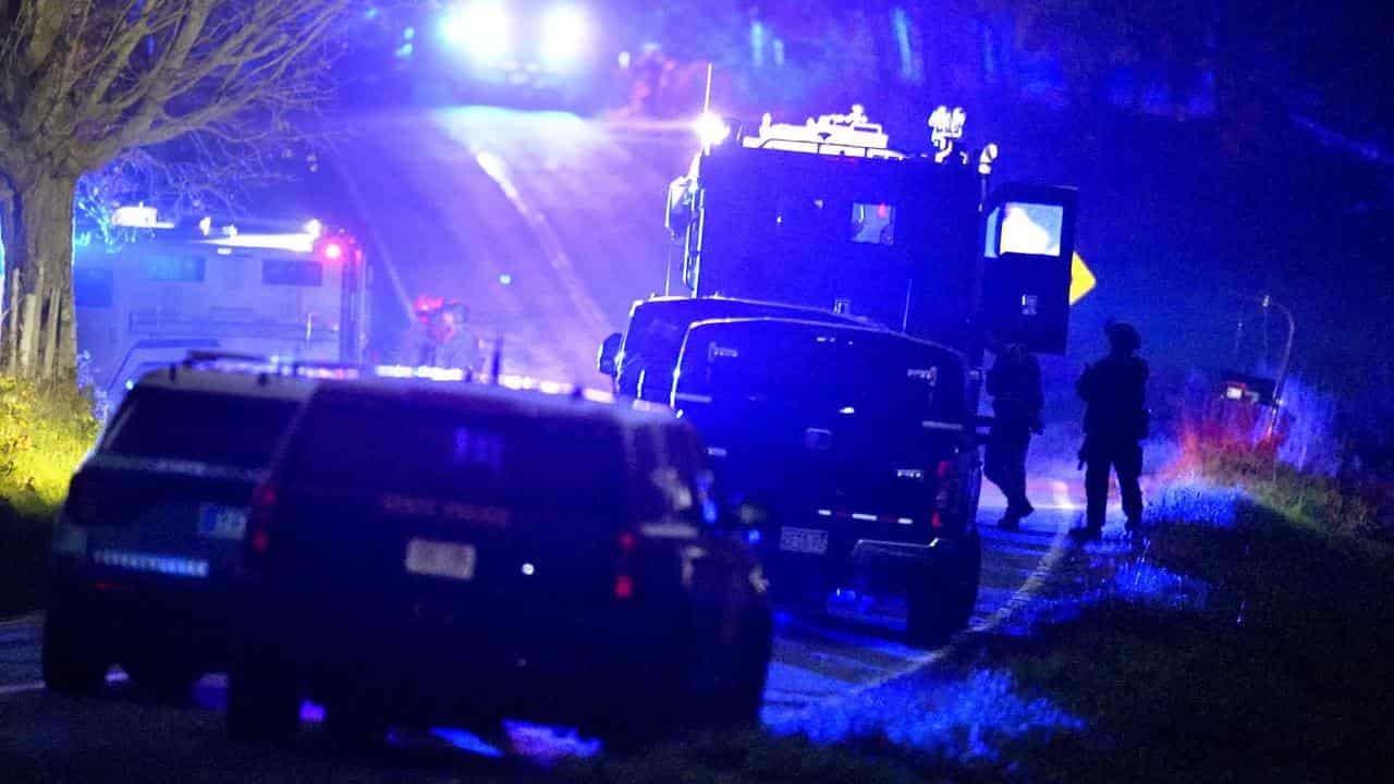 Law enforcement officers stand near armored and tactical vehicles