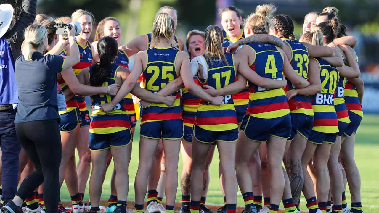 Adelaide players singing the club song in a huddle.