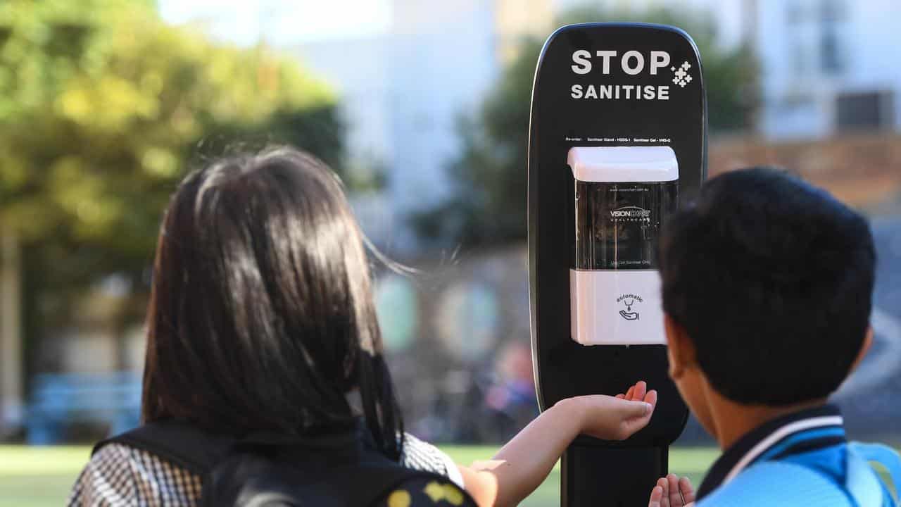 Children use hand sanitiser.