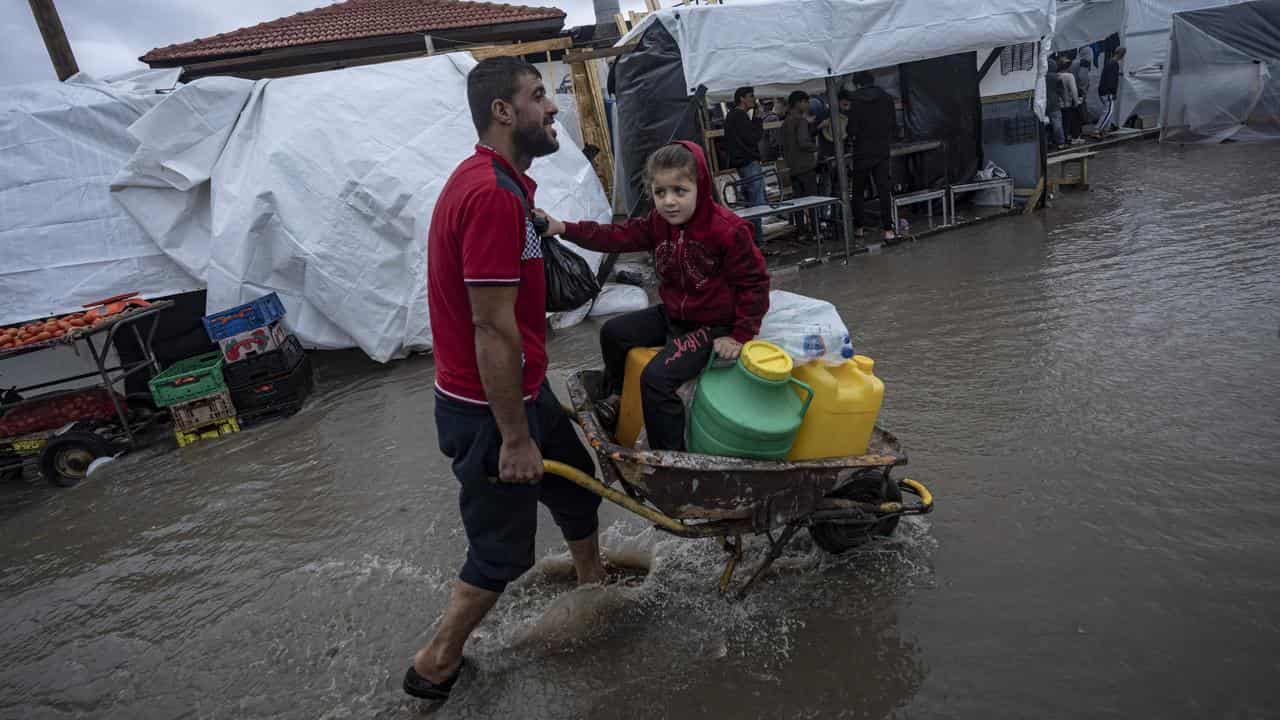 A man carries his daughter in a wheelbarrow