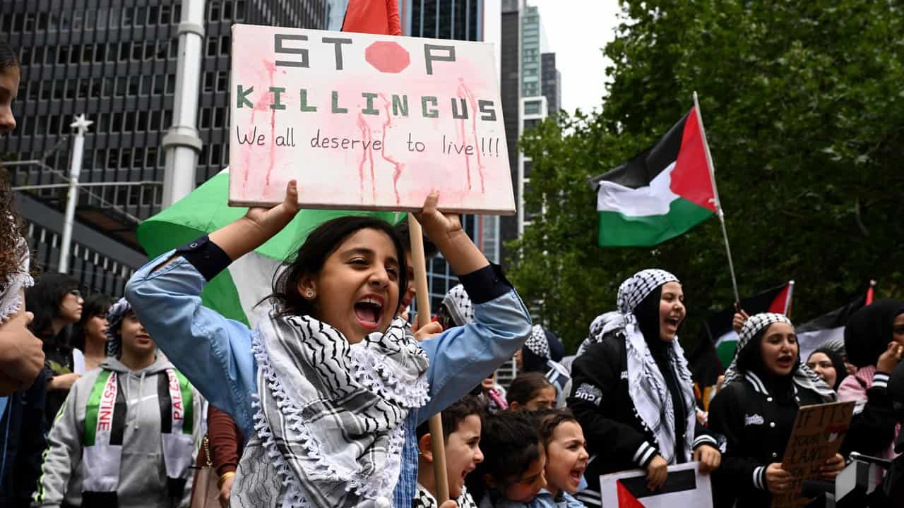 A young girl holds a sign in the crowd of young people at the rally.