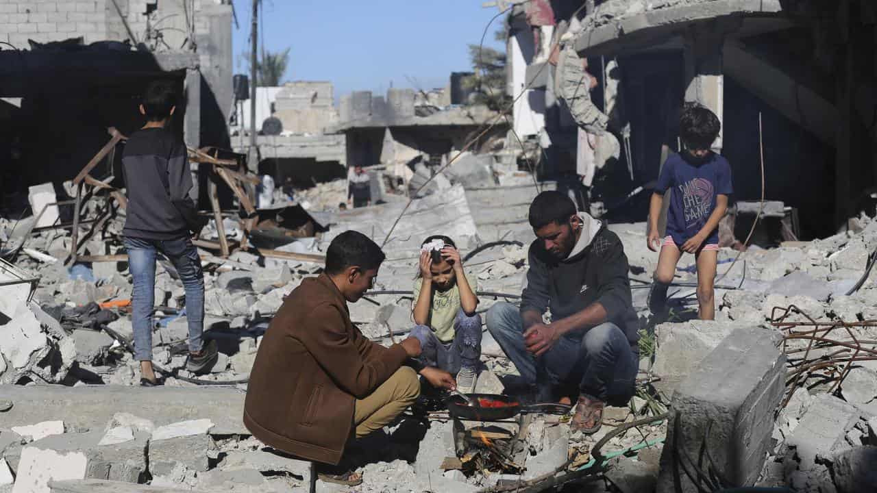 Palestinians cook bread by their destroyed homes in Gaza