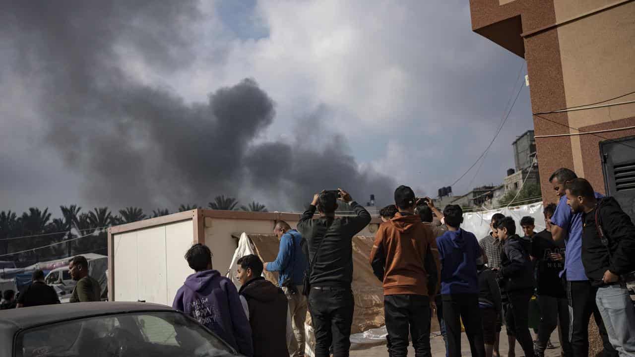 Palestinians look at smoke following an Israeli airstrike