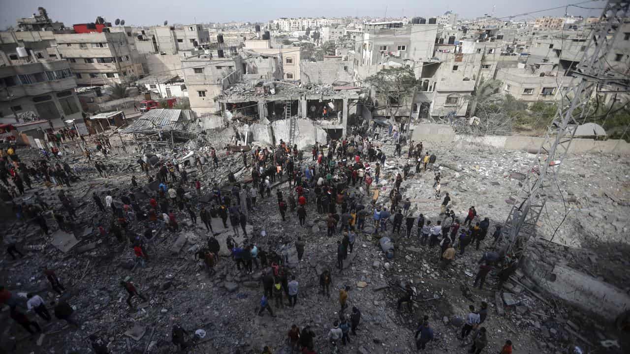 Palestinians inspect the damage of a destroyed building