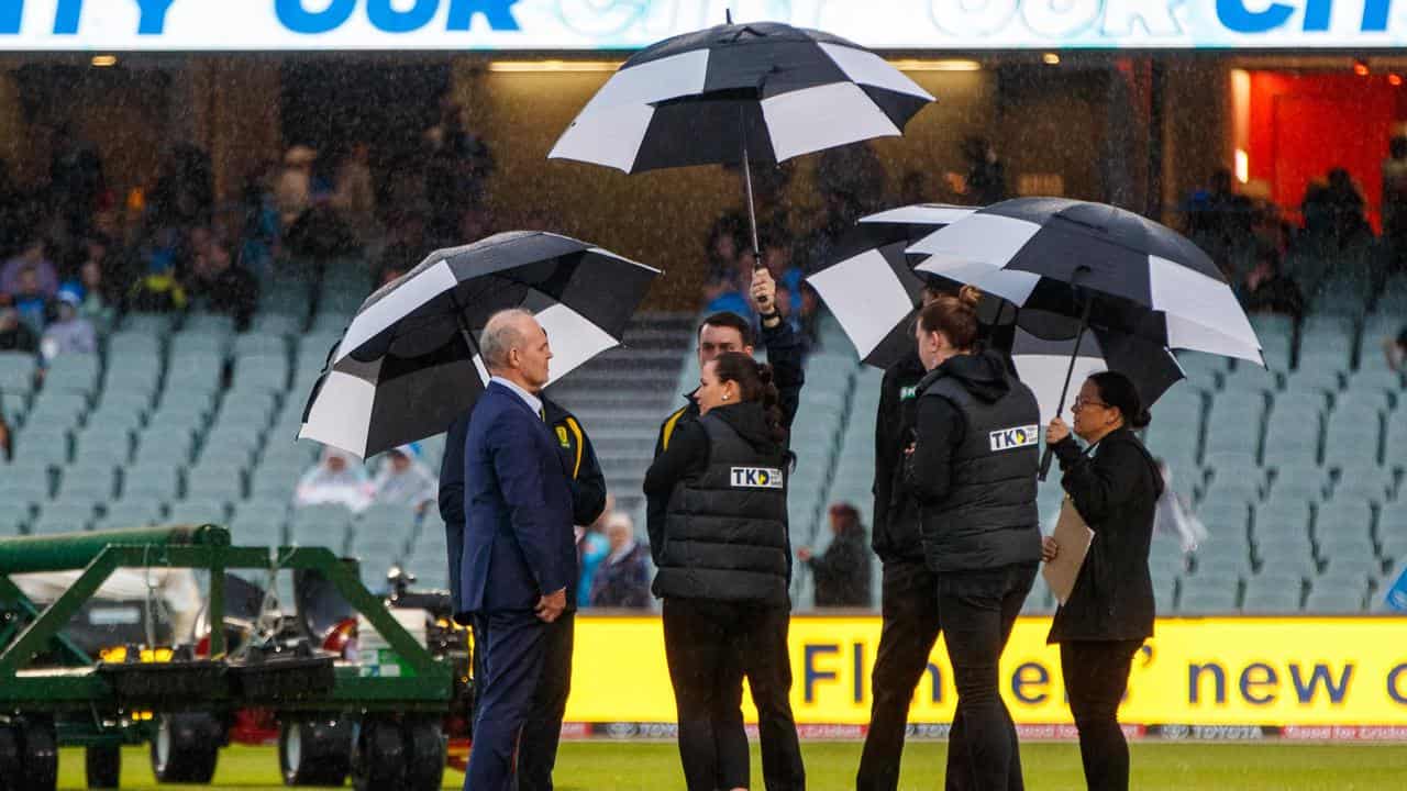 Match officials under umbrellas.