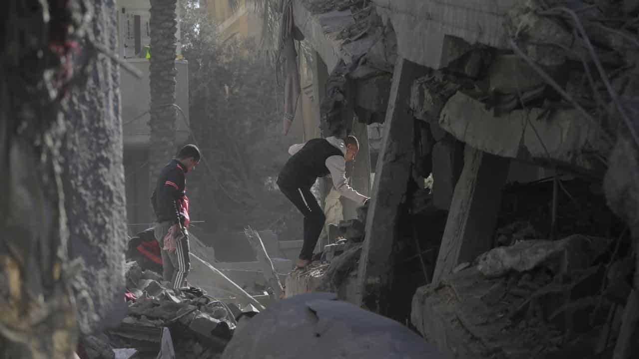 Palestinians searching the rubble of a destroyed house for survivors