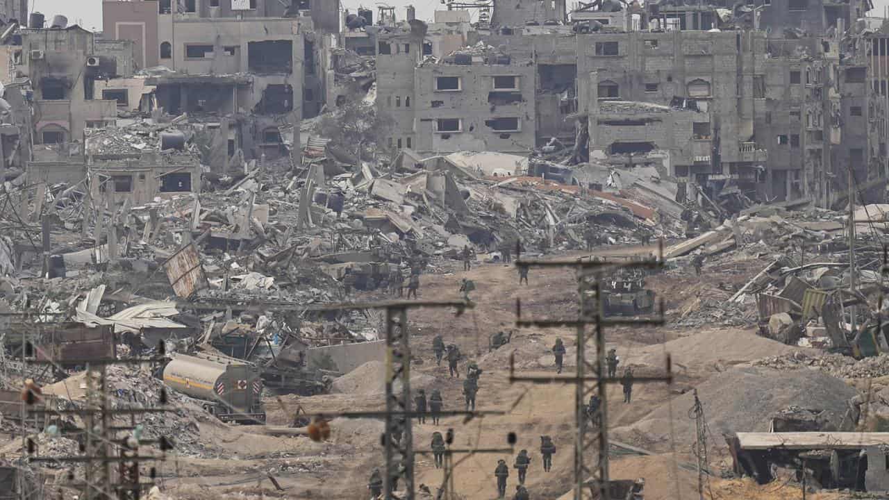 Israeli troops walk in the Gaza Strip as seen from southern Israel