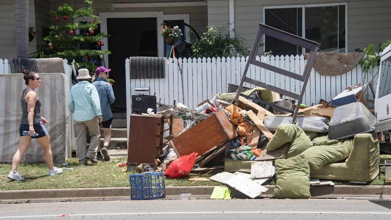 Volunteers and furniture outside a home damaged by flooding in Cairns.