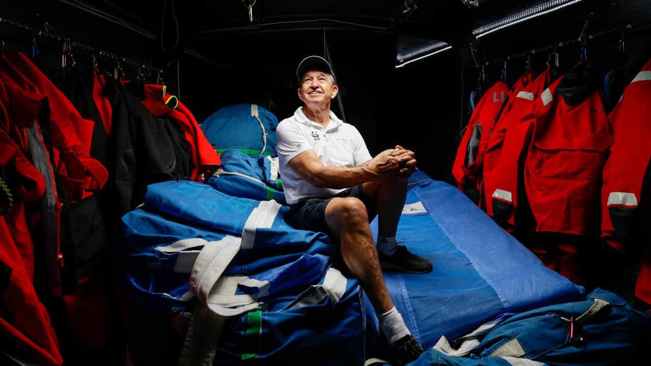 David Griffith sits on top of his sails below the deck of Whisper