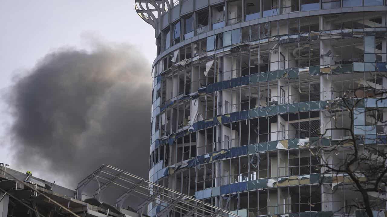 Smoke rises behind a building damaged in Kyiv