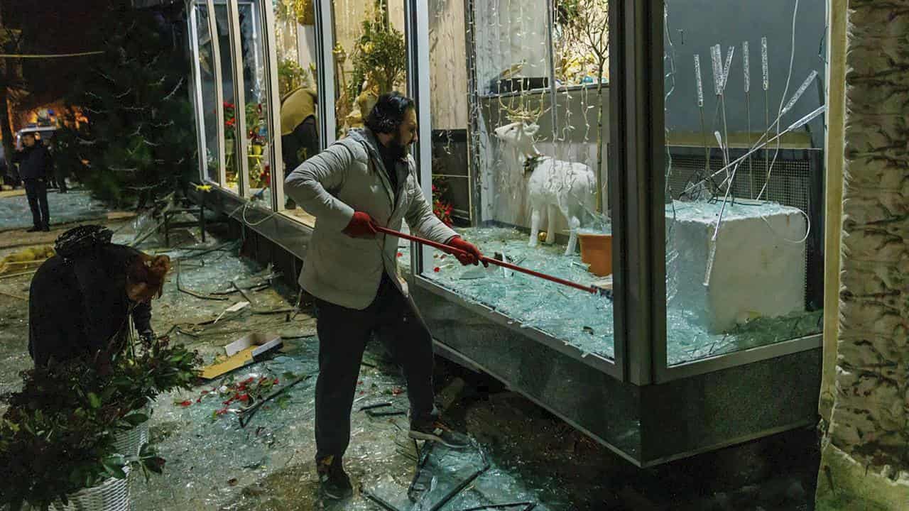 A man clears broken glass in a storefront