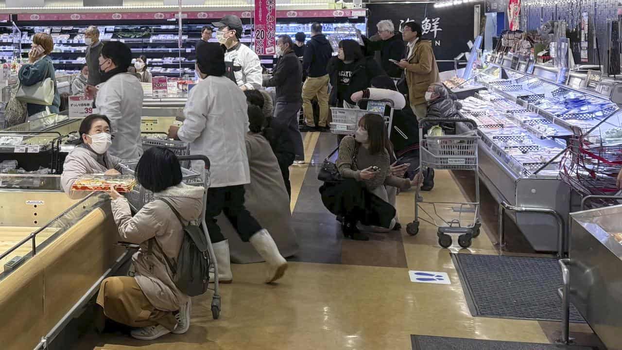 People crouch in a supermarket