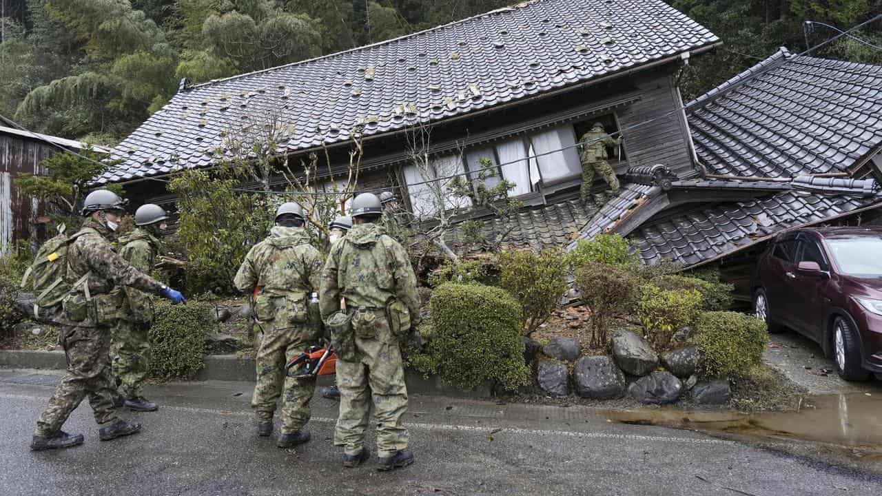 Defence members inspect a collapsed house 