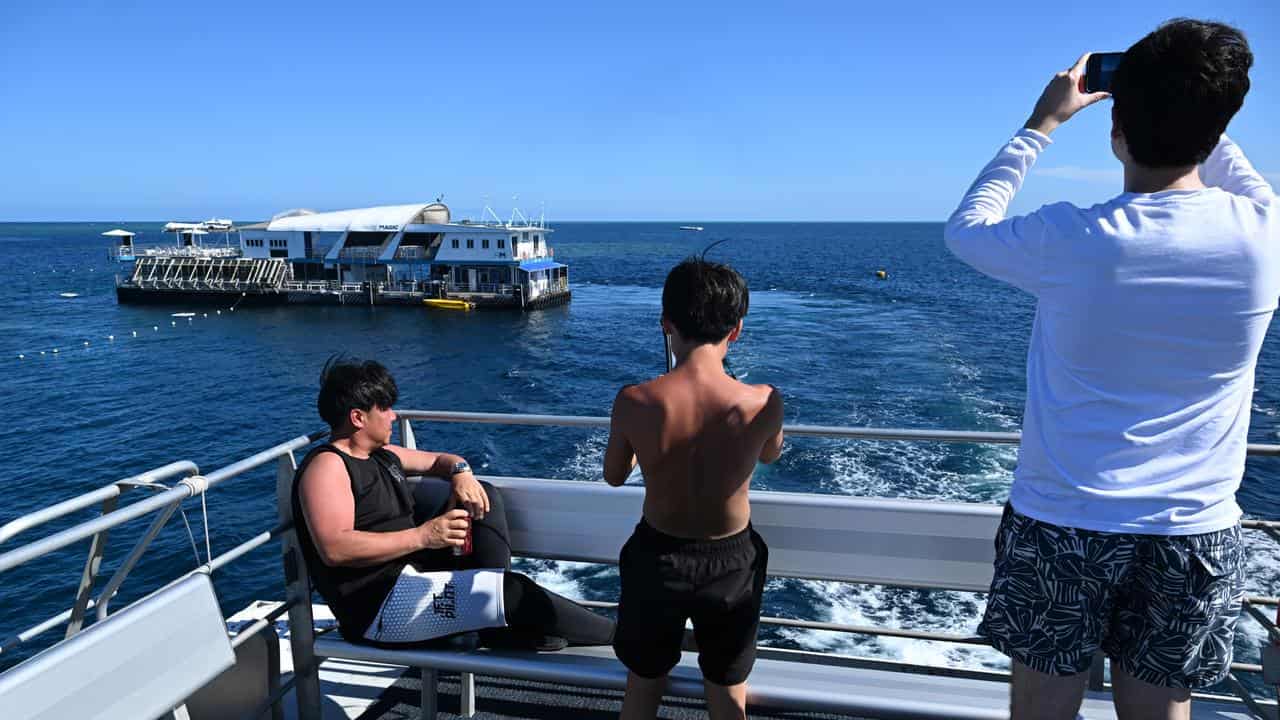 Tourists taking photographs of the Reef Magic pontoon at Moore Reef