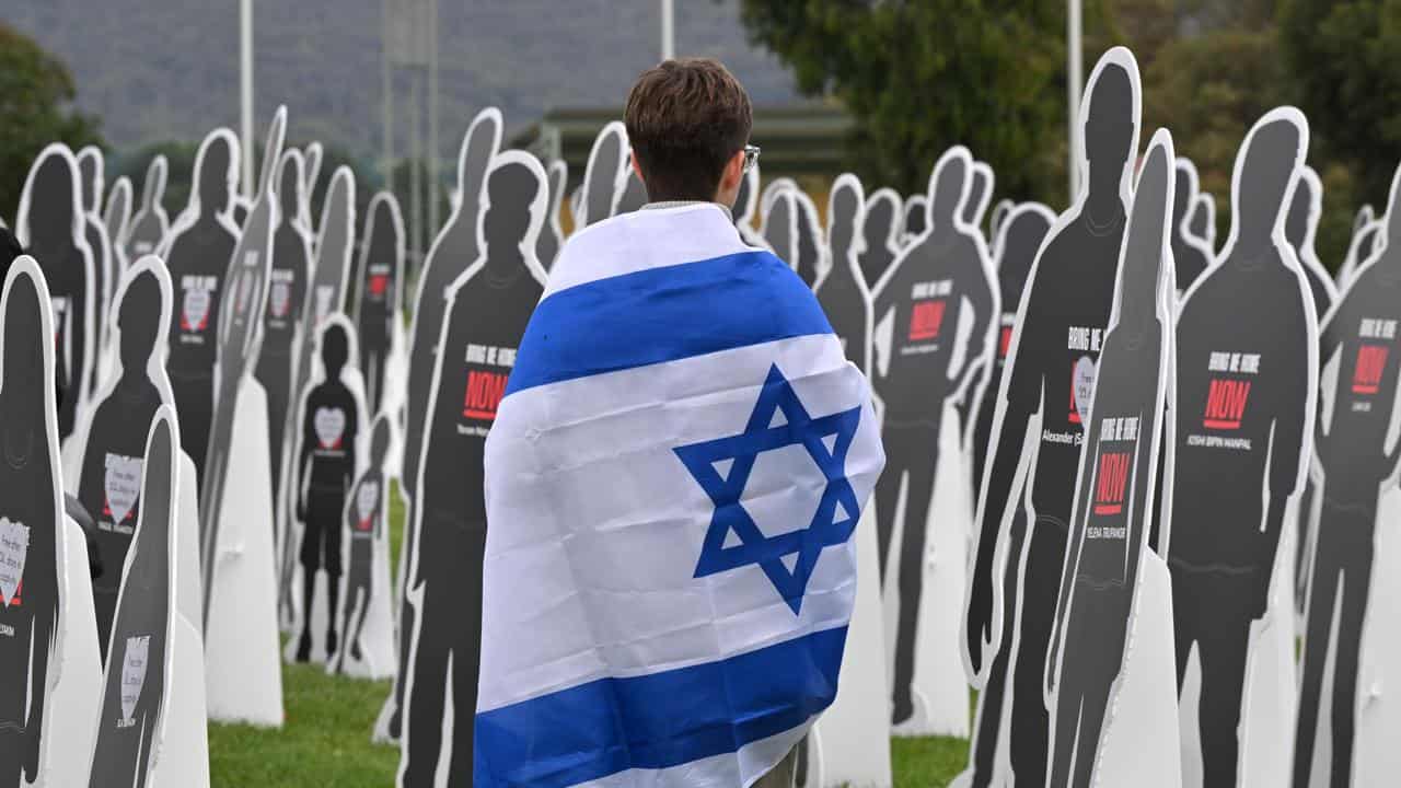 Protester with an Israeli flag walks past cutout cardboard effigies.