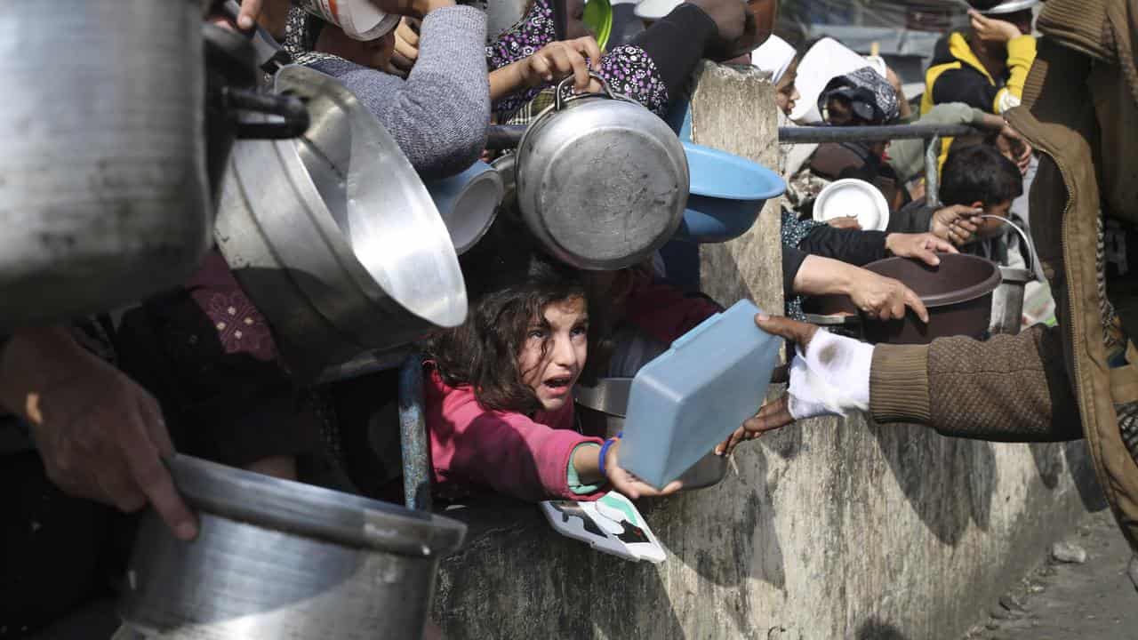 Palestinians line up for food during the ongoing Israeli assault