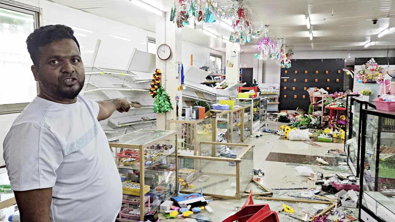 A man points to damage from looters