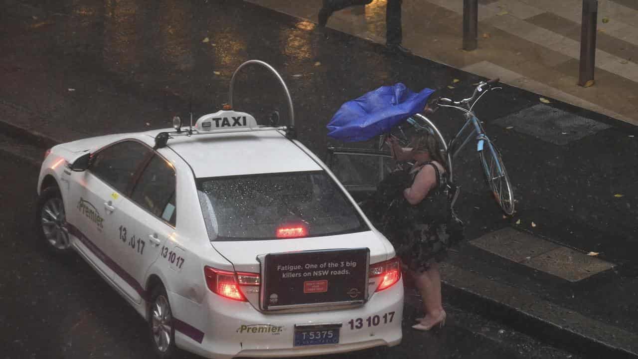 A women walks through late afternoon rain in Sydney