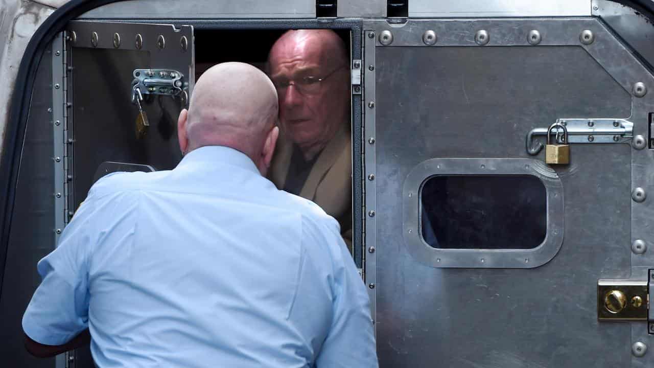 Former detective Roger Rogerson is escorted to a prison van 