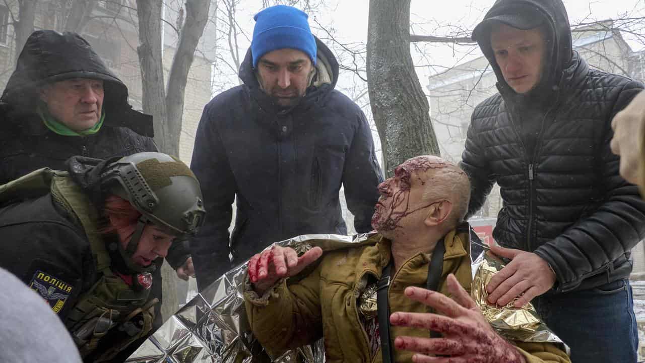 Locals help an injured man at the site of a rocket attack in Kharkiv