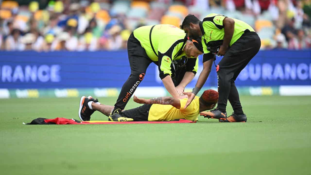 A pitch invader carrying a Aboriginal flag is seen being apprehended