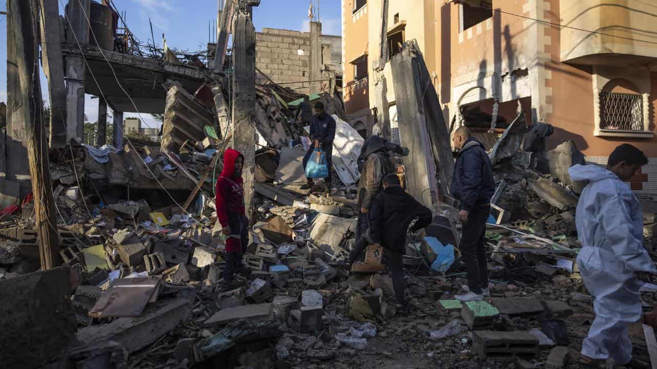 Palestinians look at the destruction after an Israeli strike in Rafah