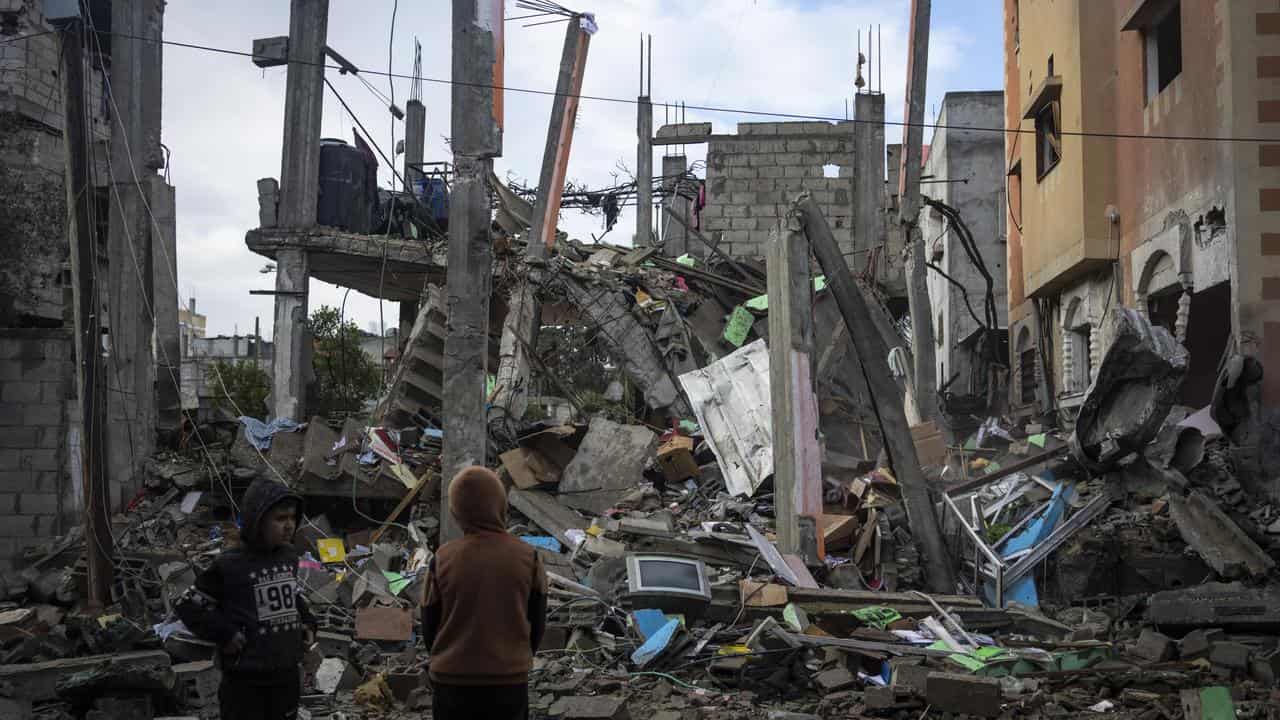 Palestinians look at the destruction after an Israeli strike