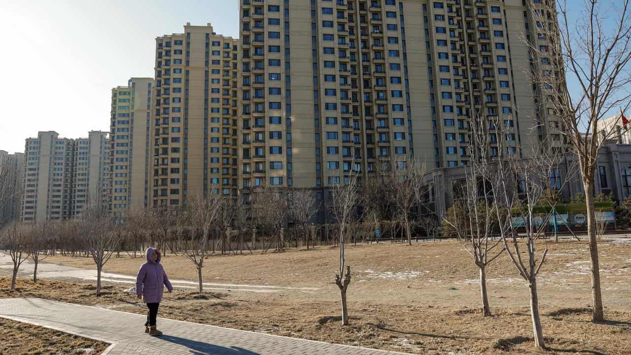 A woman walks next to an Evergrande housing complex in Beijing, China