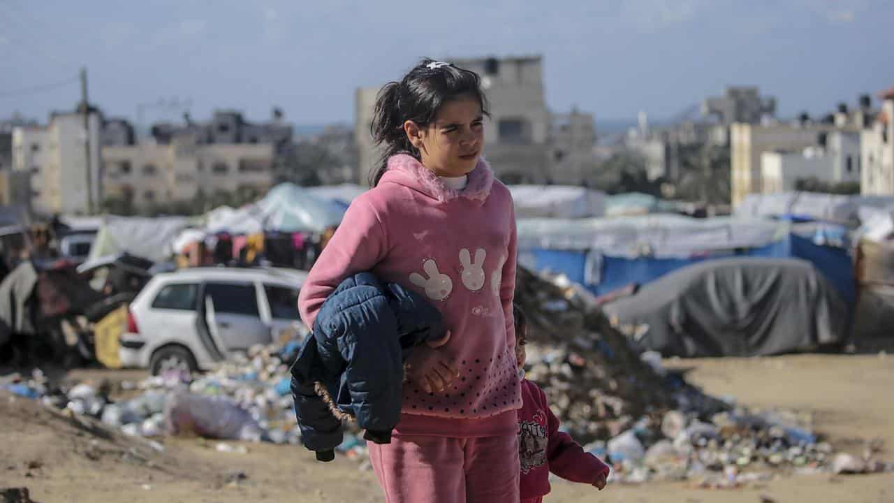 A Palestinian girl walks near a shelter in Deir Al Balah, Gaza Strip