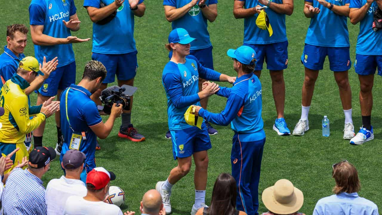 Fraser McGurk (left) is handed his Australia debut cap by Adam Zampa.