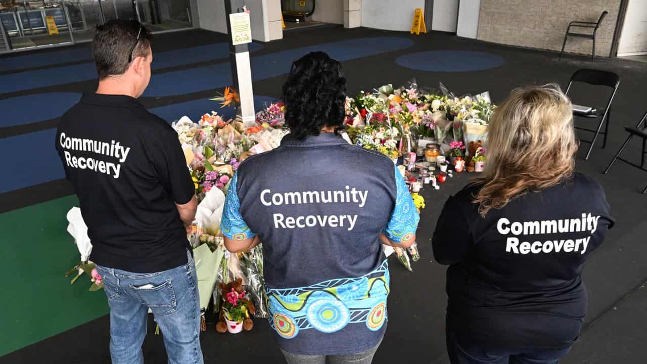 Three people at the memorial at the shopping centre.