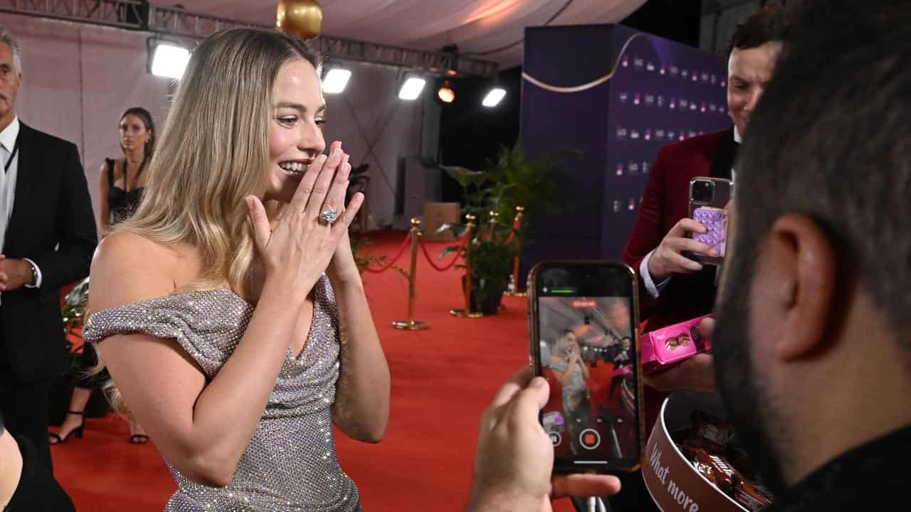 Margot Robbie reacts to being given Tim Tams on the AACTA red carpet.