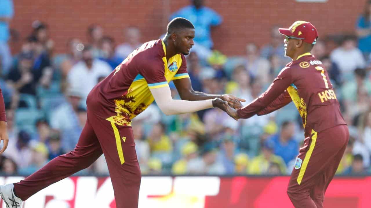 Jason Holder celebrates a wicket with team mate Akeal Hosein.