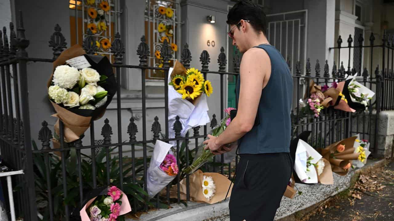 A man placing flowers at the home of Jesse Baird in Sydney