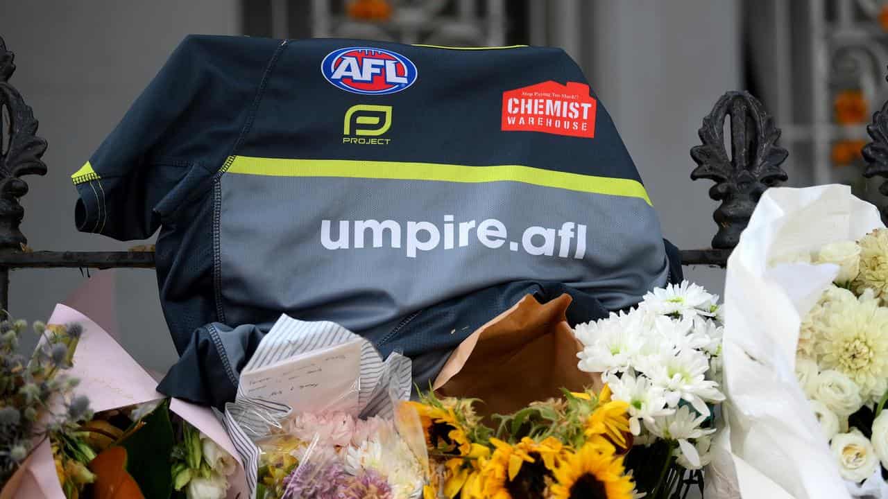 An AFL umpire’s guernsey among floral tributes at Paddington.