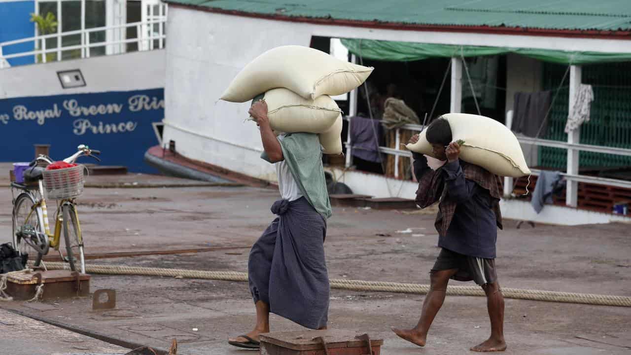 Workers carry rice bags at a jetty in Yangon, Myanmar