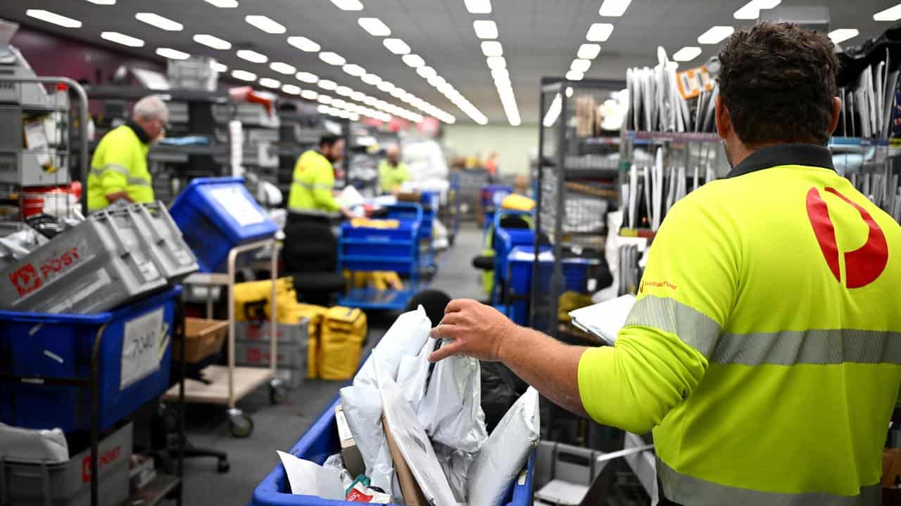 Post office workers sort the mail.