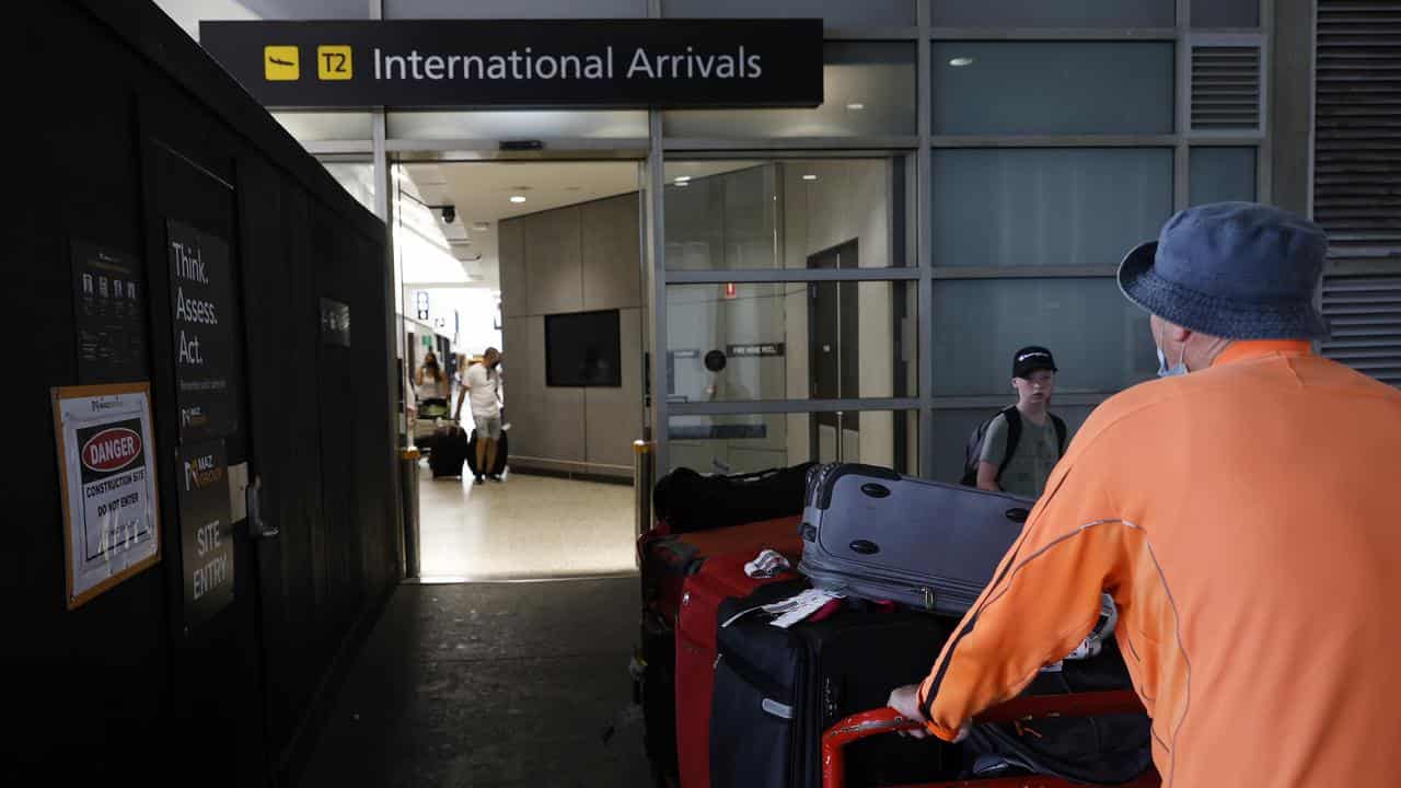 A man pushing a trolley full of passenger bags at an airport