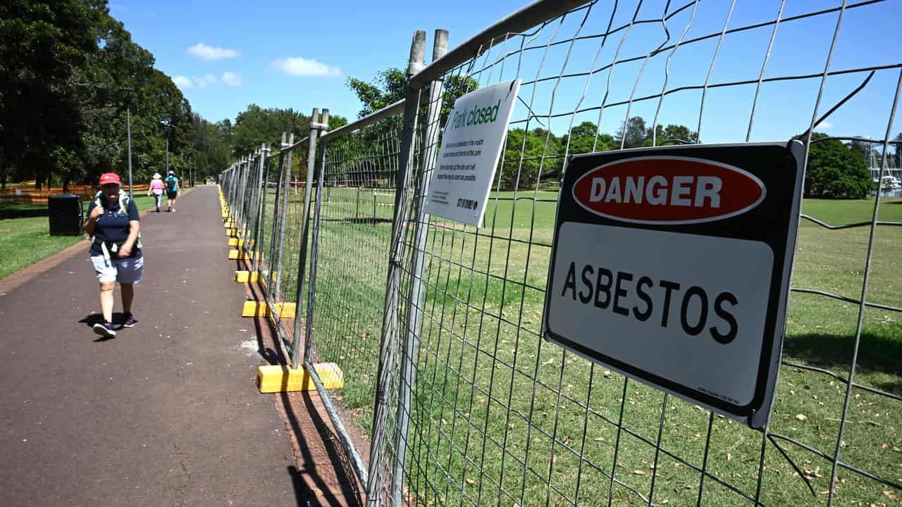 A sign saying DANGER Asbestos on fencing around a park