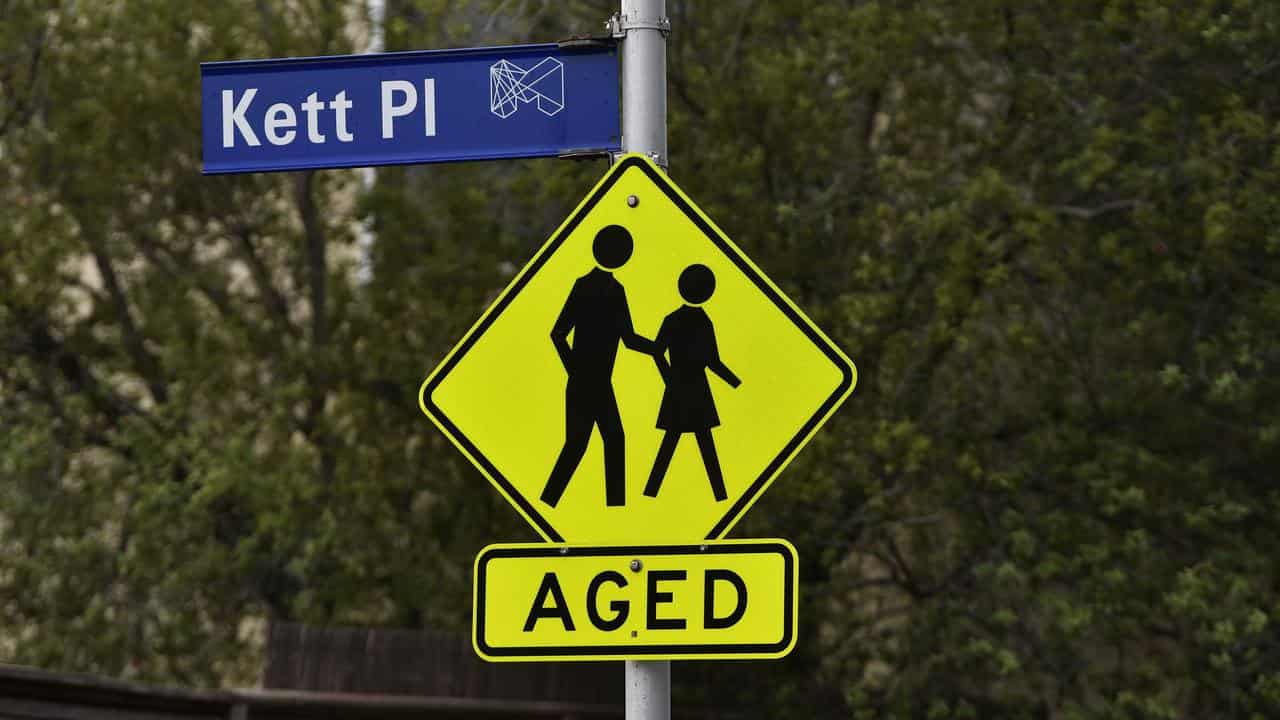 A hazard sign warning drivers of elderly people crossing.